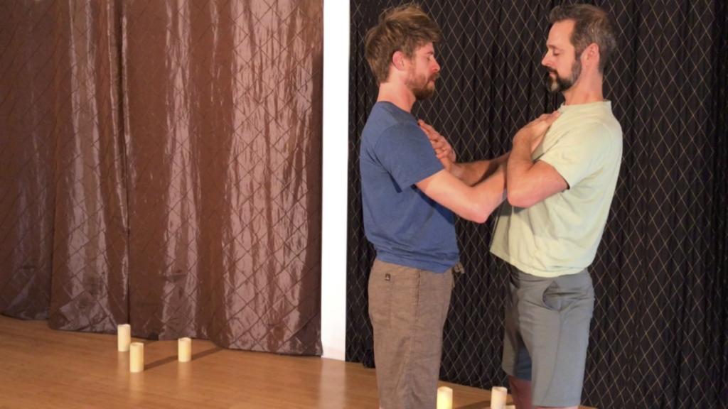 2 men standing a dance hall with one hand on their own heart and their other hand on the others heart